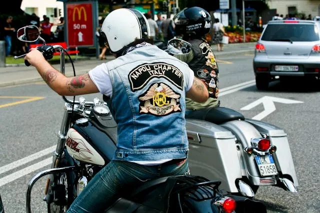 a man in a denim vest riding a motorcycle for biker patches meaning
