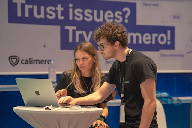two people looking at a laptop for what to bring to a trade show booth two people looking at a laptop for what to bring to a trade show booth
