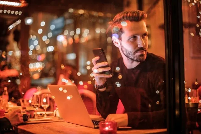 a man with a laptop holding a smartphone for how to open a bar