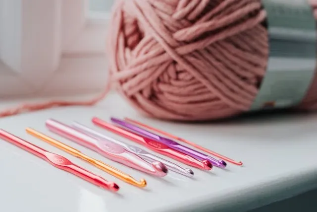 colored crochet needles and yarn on a windowsill for scarf crochet pattern