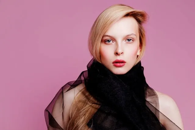 a person wearing a black scarf against a pink background for how to store scarves