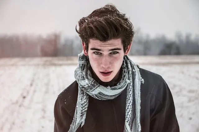 a person wearing a gray scarf in a snowy field for how to store scarves