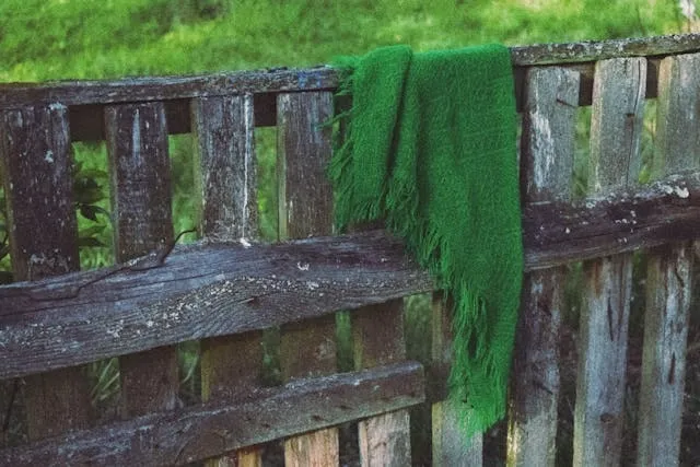 a vibrant green scarf on a rustic wooden fence for different fringes for scarves