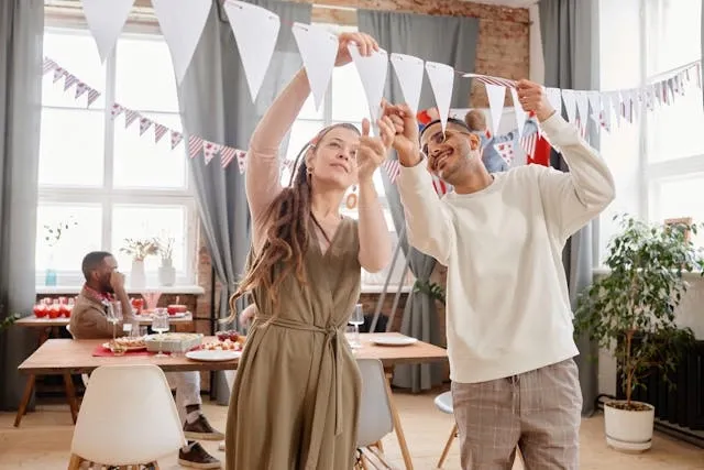 people hanging paper decorations for diy party decorations