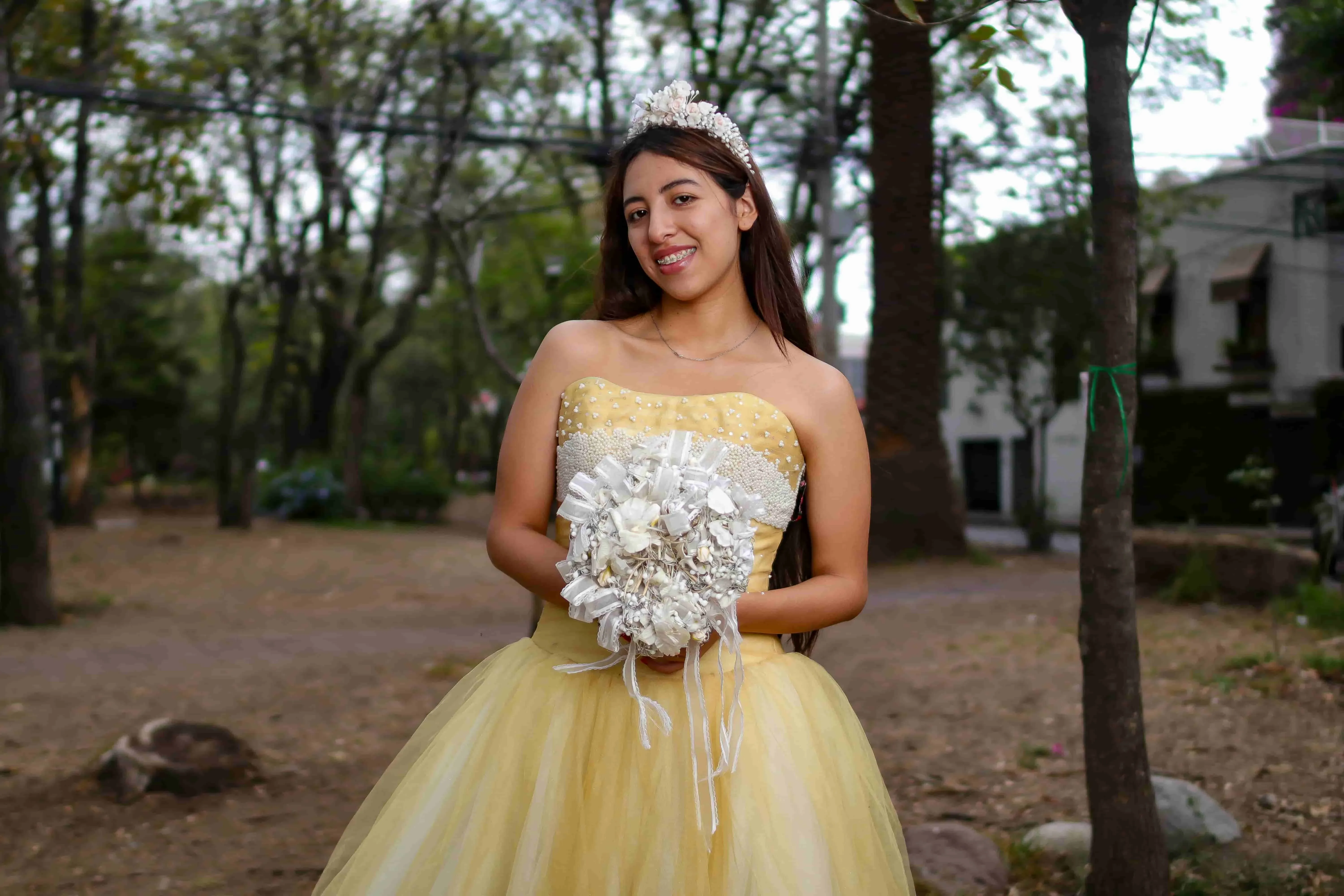 a young woman in a yellow gown outdoors for quinceanera backdrop ideas