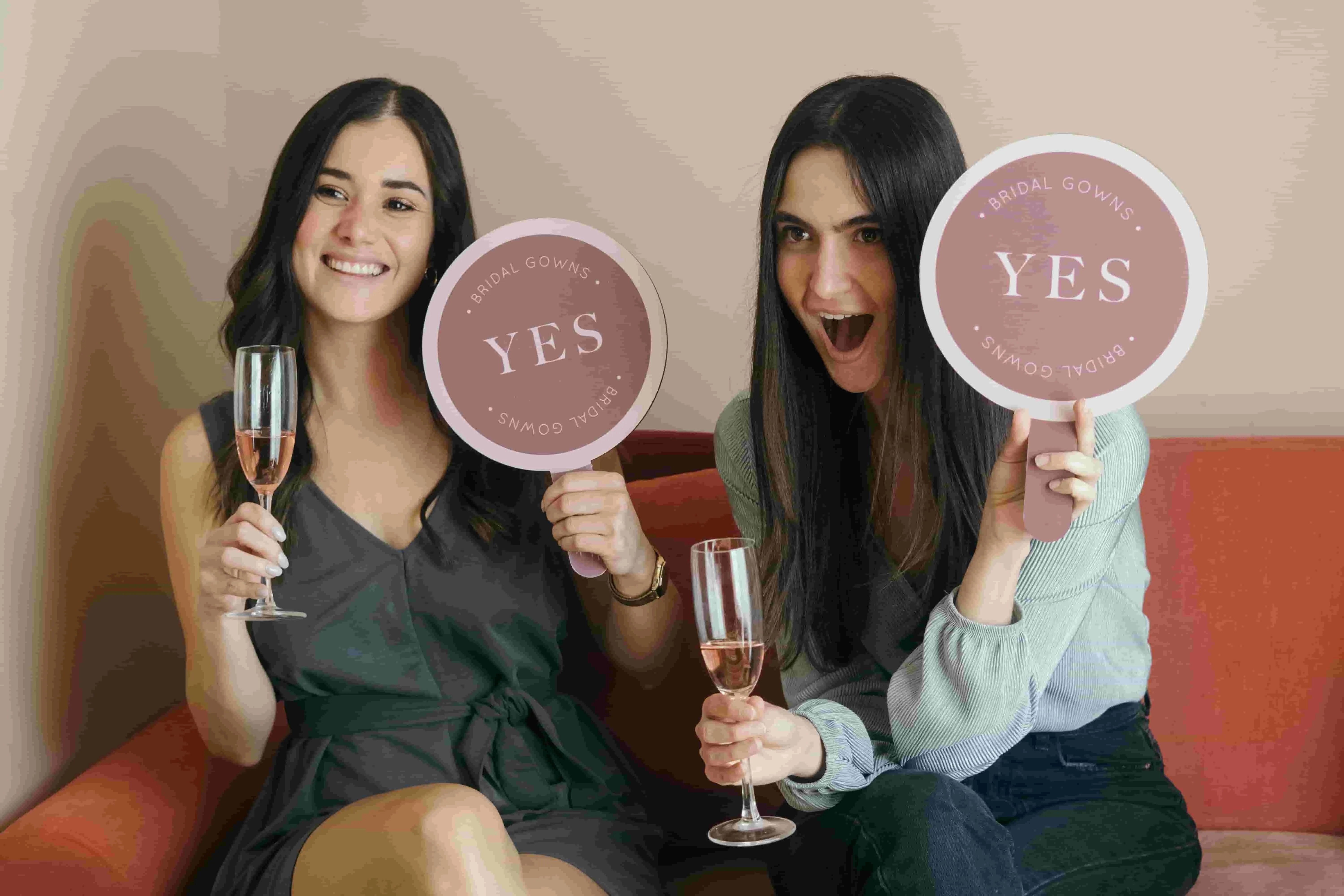 two women holding drinks and signs for engagement party ideas