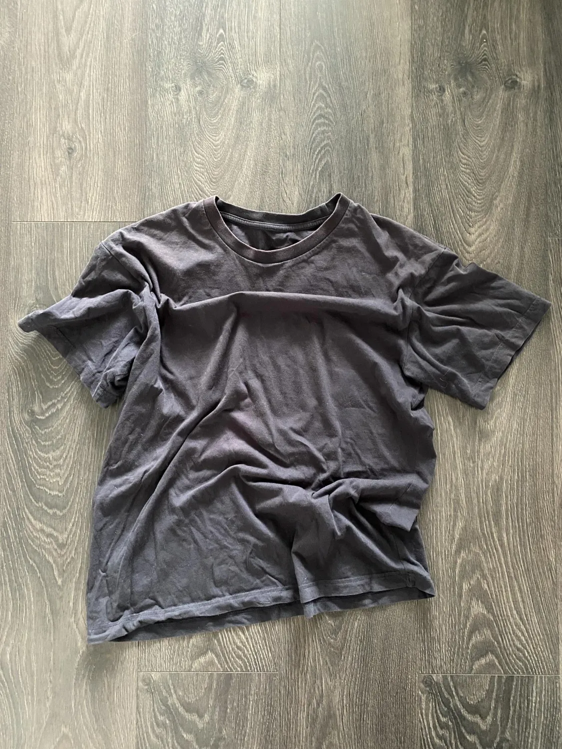 Black tshirt without a pattern for a logo lying on a black background crumpled