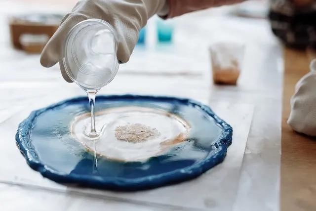 a person pouring resin into a mold for how to make resin coasters