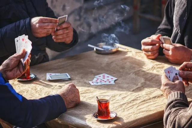 people playing cards around a square table for tablecloth square sizes