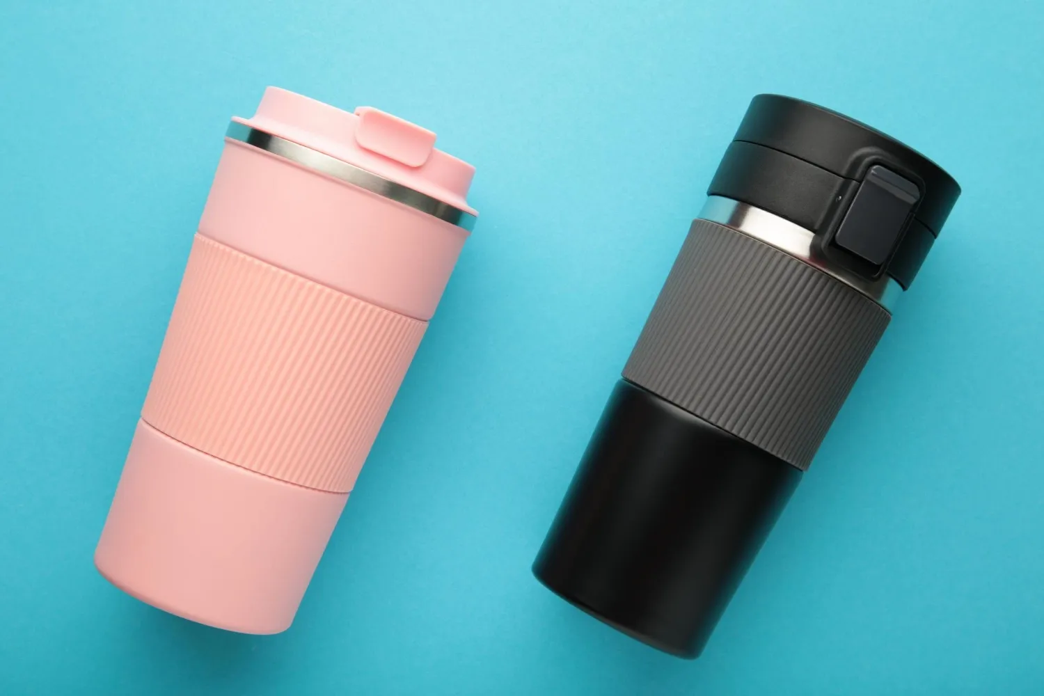Two thermo cups or thermos mugs for tea or coffee on blue background black and pink for him and her hot beverage for couples