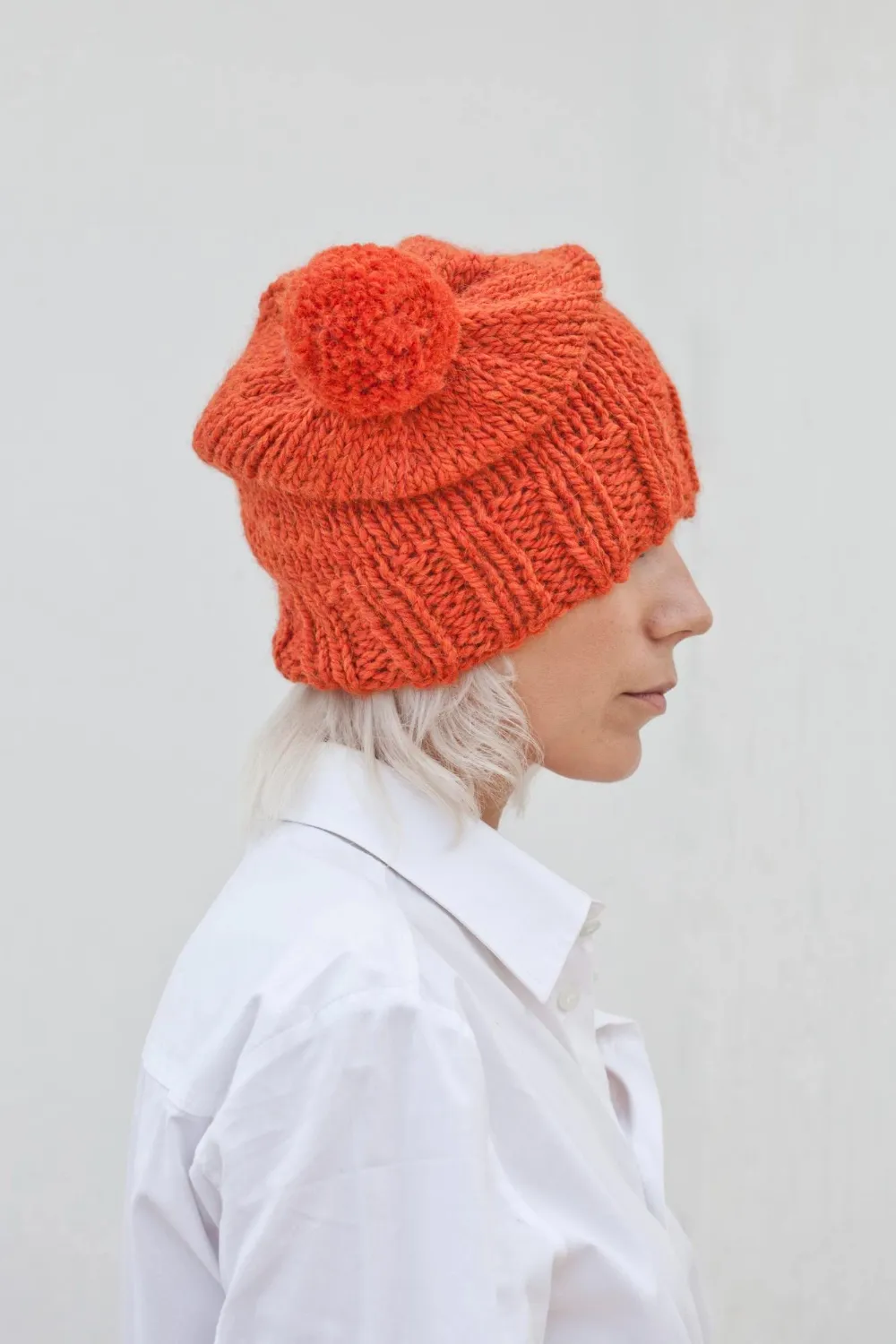 Pretty young woman in warm orange beanie wool knitted hat