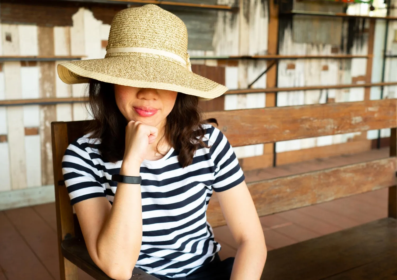 Smiling woman with hat sitting on wooden bench