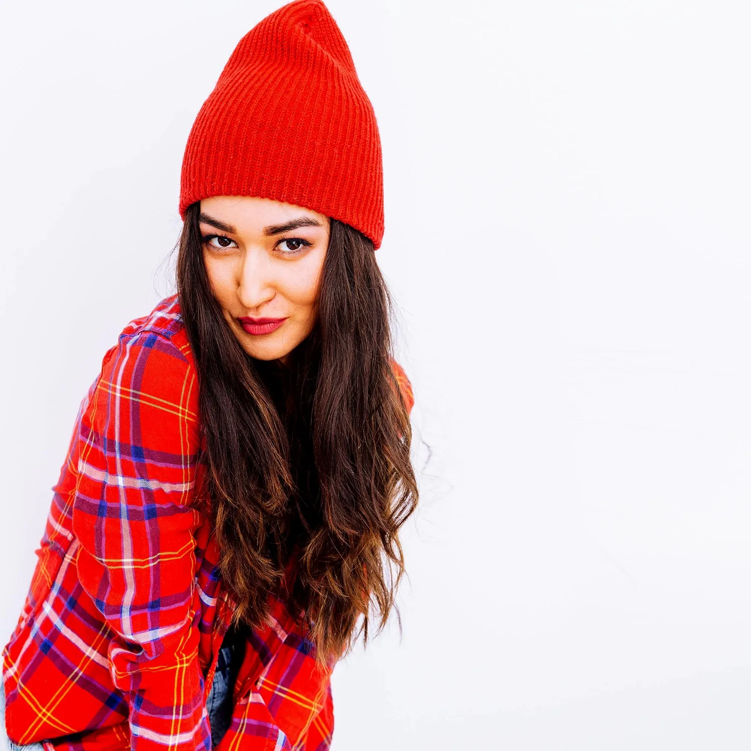 Stylish brunette girl urban fashion look checkered shirt and beanie cap red vibes