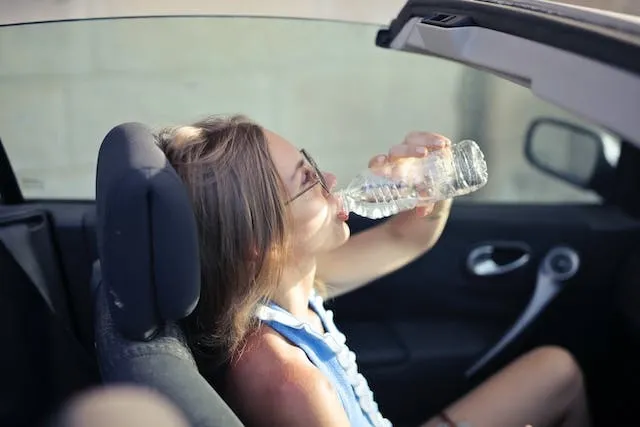 woman drinking water in a car
