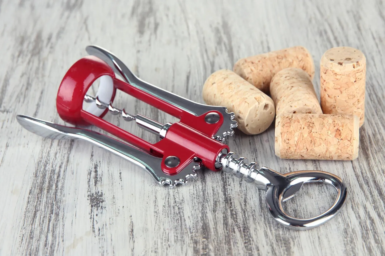 Corkscrew with wine corks on wooden table closeup
