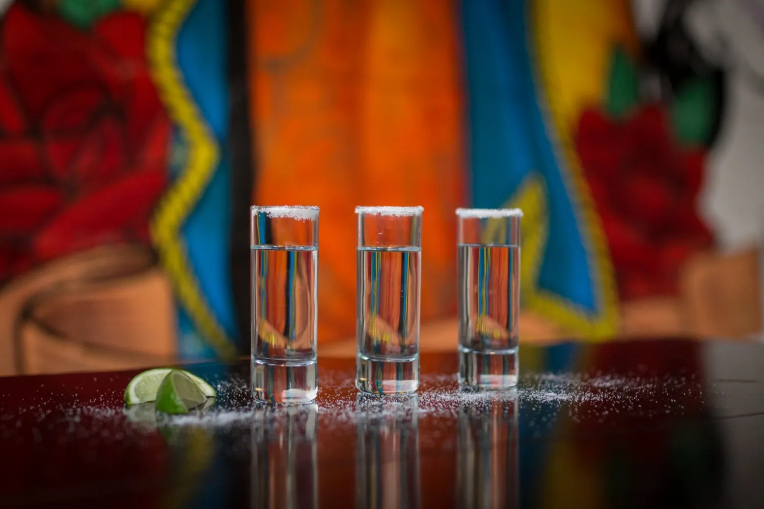 Glasses of tequila, salt and lemon on mexican colorfull background