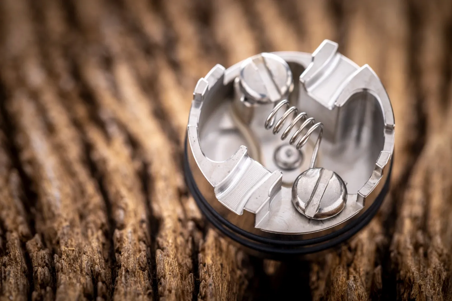 Close up shot of single space coil in high end rebuildable dripping atomizer for flavour chaser on rustic natural wood texture background, vaping device