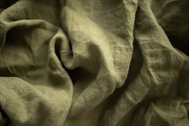 an example of some creased green fabric for how to fold round tablecloths to avoid wrinkles