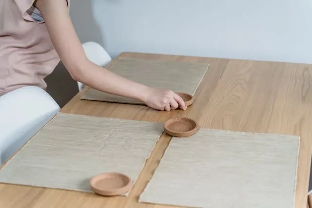 a woman laying placemats on a table for table runner or placemats