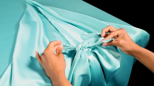 a blue tablecloth being tied at the corners for how to tie tablecloth corners