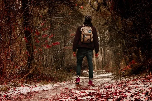 a man carrying a patched backpack on a woodland path for best backpacks for patches