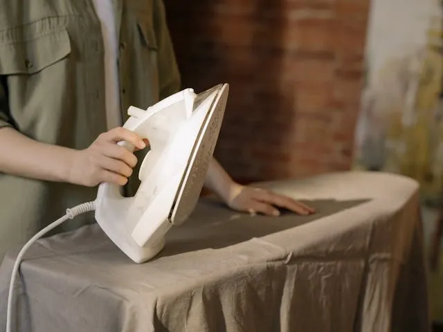 a person holding an iron to some fabric for iron on vs sew on patch