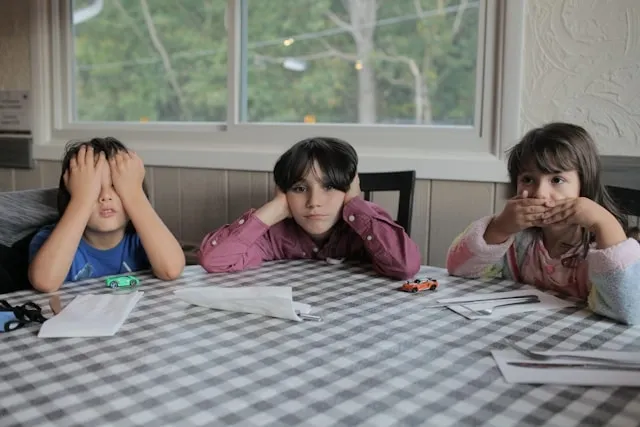 children sitting beside an undecorated plastic tablecloth for how to make plastic tablecloths look nice