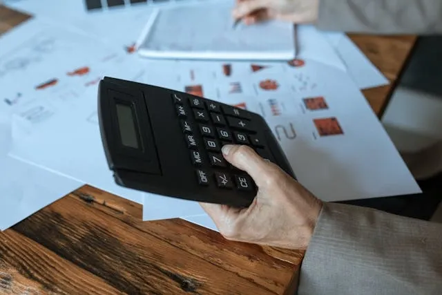 a person performing calculations with paperwork and a calculator for event budgeting