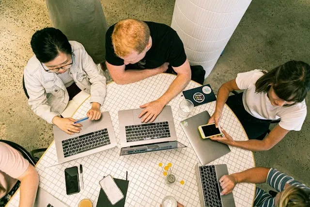 a team sat around a table with laptops for event paneer marketing