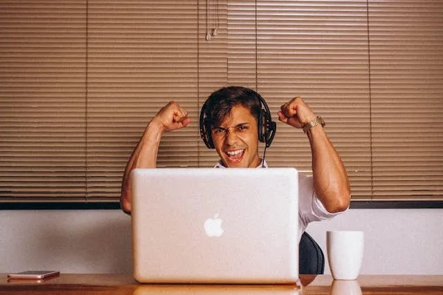 a person cheering whilst sitting in front of a laptop for employee appreciation gifts