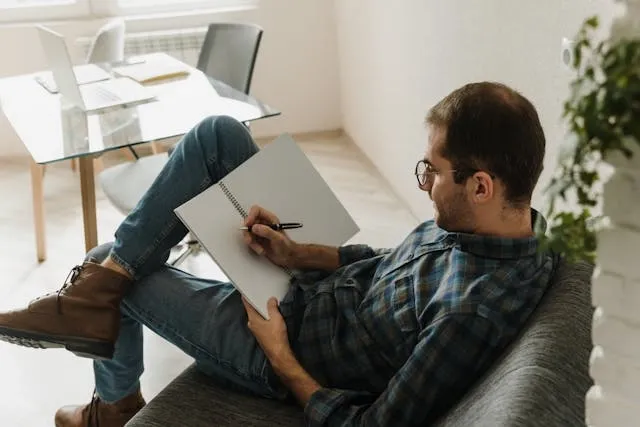 a man wearing jeans while sitting with a notepad for types of jeans men