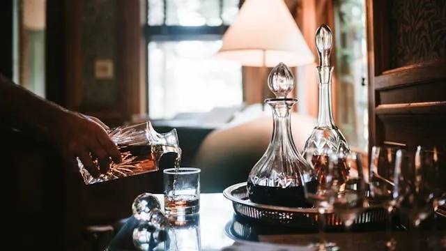 a person pouring a drink at home from a decanter for gifts for bourbon lovers