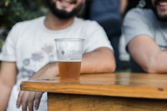 some people sitting at a table with beer in a plastic cup for mobile bar business