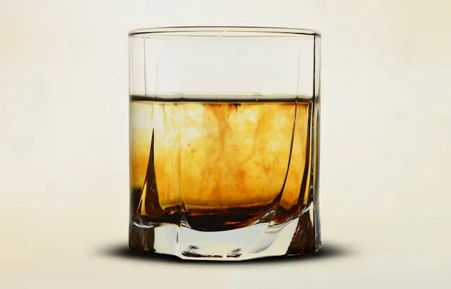 a close-up photograph of a whiskey glass with a brown liquid in it for gifts for bourbon lovers