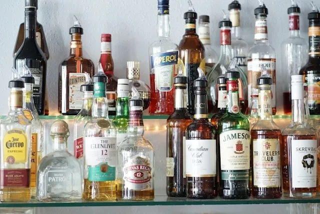 a shelf filled with lots of bottles of liquor for how to organize liquor cabinet