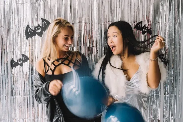 two people having fun in a photo booth with bat decorations for cocktail party themes