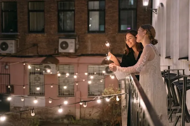 two people standing on a balcony above string lights for party lighting ideas