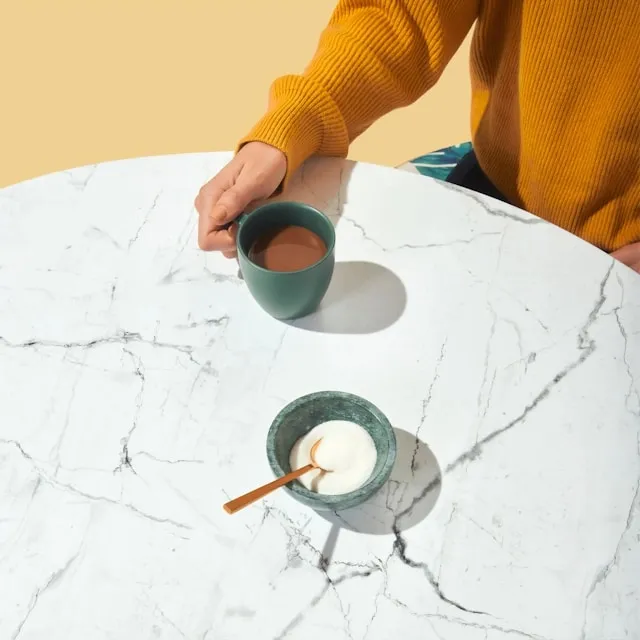 a person drinking coffee at a circle table for how many chairs fit around a 60-inch round table