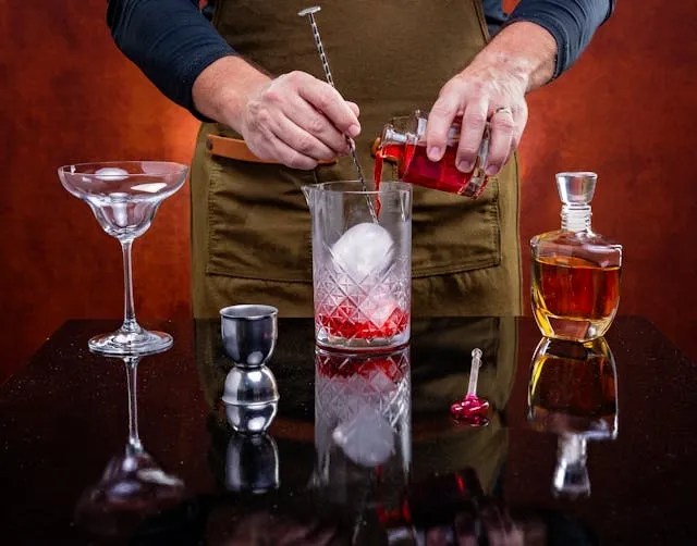 a person preparing a cocktail for wedding cocktail table decor