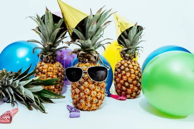 three pineapples surrounded by party decorations for party planning checklist