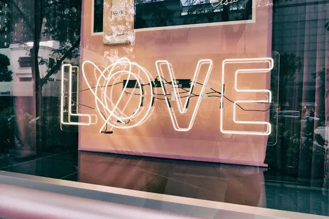 a white neon sign in daylight that says love for how are neon signs made