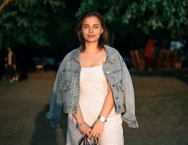 a person with a denim jacket draped over their shoulders for how to style a jean jacket