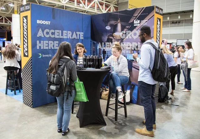 company representatives engaging visitors at a booth for trade show booth ideas