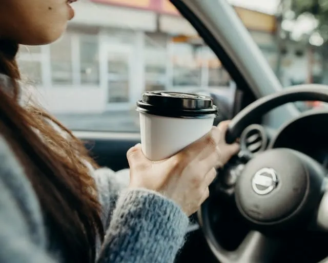 a person driving a car while holding a coffee cup for car coaster designs