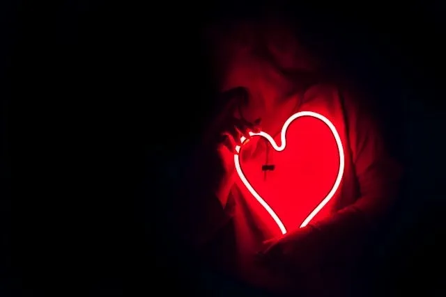 a person holding red neon flex bent into a heart shape for diy neon sign