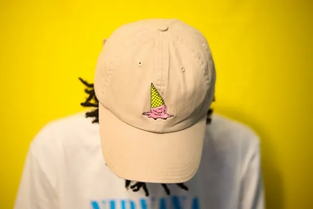 a person wearing a baseball cap in front of a yellow backdrop for iron patch onto hat