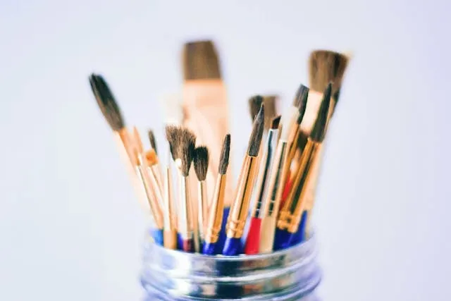 a selection of paint brushes in a glass jar for coaster painting ideas