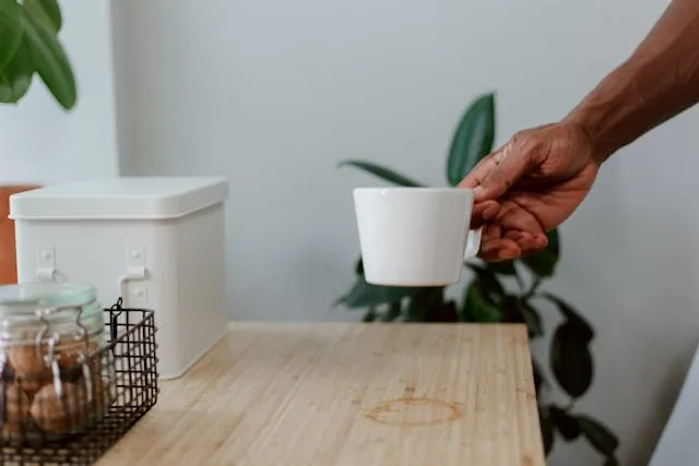 a person lifting a cup from a table and leaving a moisture ring for how to get water stains out of wood tables