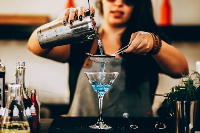 a woman pouring liquid from a drink mixer for what are the essential items needed to bartend