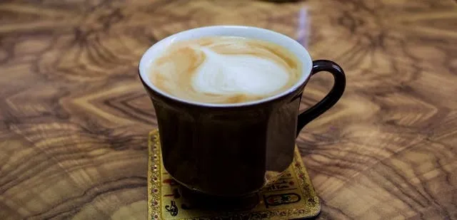 a mug of coffee on a coaster atop a wood table for how to get water stains out of wood tables